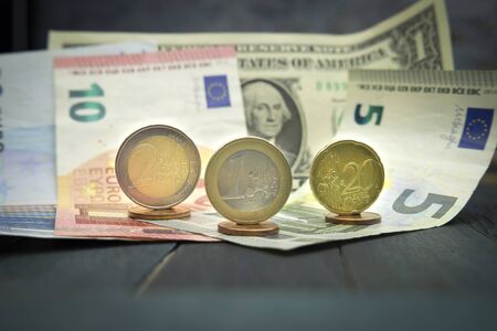 Close-up of Euro and USD cash money with various coins of Euros and cents over banknotes on black...