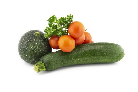 Green round and traditional courgette or zucchini, cherry tomato twig and fresh parsley sprigs isolated on white backgroundの写真素材