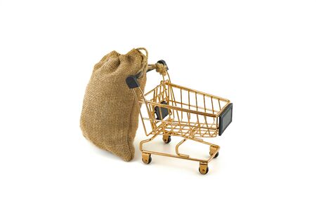 Empty golden shopping cart and jute bag isolated on white backgroundの写真素材