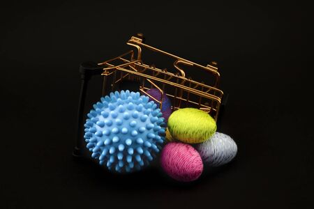 Blue virus molecule, shopping cart and creative colorful eggs made from yarn conceptual of the possibility of infection with corona virus or Covid-19 over a black backgroundの写真素材