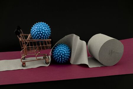 Corona virus or Covid-19 stockpiling of toilet paper or paper towel concept with a roll, shopping cart and two blue virus models over a red banner and dark backgroundの写真素材