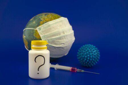 Concept of research for a Covid-19 vaccine with a hypodermic syringe, pharmaceutical bottle and blue...