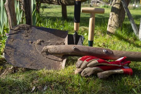 Garden spade or shovel with gloves and tools outdoors on a green lawn in a concept of spring gardeningの写真素材