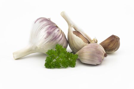 Garlic bulbs, cloves and green parsley twig in close-up isolated on white backgroundの写真素材