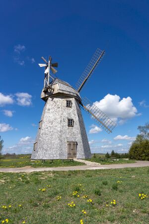 Historic windmill in a lush green field in spring against a sunny blue sky in a scenic landscapeの写真素材