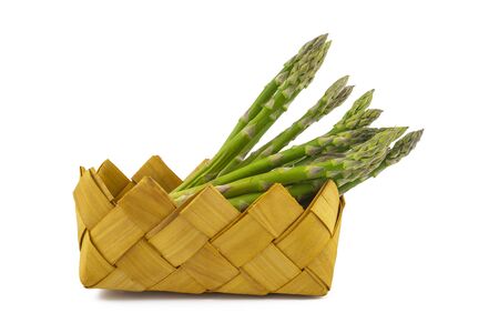 Bundle of fresh green asparagus in a rustic woven basket isolated on white background, selective focus in a low angle viewの写真素材