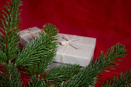 Christmas still life with a gifts and pine branches over a festive red background with vignette and copy space for a seasonal greetingの写真素材