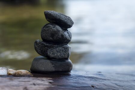 Small stack of pebbles or stones in a stream carefully balanced on each other with rippling sunlit water flowing pastの写真素材