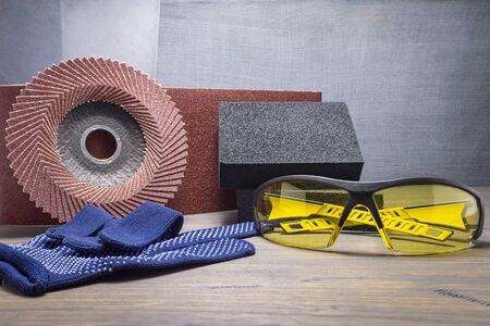 Various grinding tools - sanding belt, abrasive sponge and flap disc for angle grinder, safety gloves and goggles, renovation, safety and health at work conceptの写真素材
