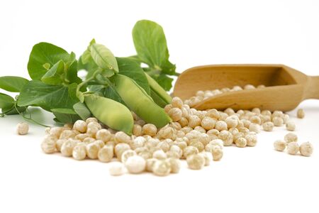 Dried peas spilling from a wooden scoop fresh plant with pods isolated on a white backgroundの写真素材