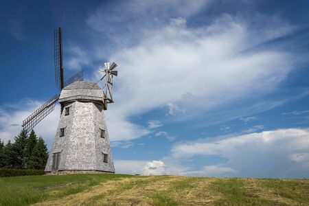Old windmill in grassland in a country landscape under a cloudy blue sky in a scenic landscapeの写真素材