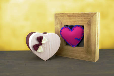 Handcrafted pink heart in a wooden frame with a heart shaped gift boxの写真素材