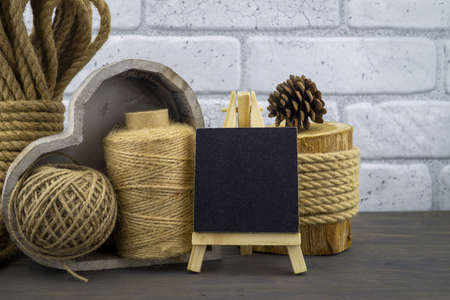 Assorted balls of hemp twine and string with skeins of rope and slate chalkboard in a close up...