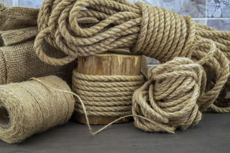 Jute rope and spools of burlap threads or jute twine in close-up on rustic wooden background