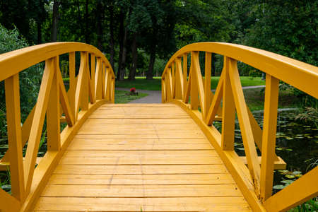 Empty arched wooden pedestrian bridge curving away in a receding perspective outdoors in a parkの写真素材