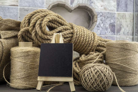 Assorted balls of hemp twine and string with skeins of rope and slate chalkboard in a close up rustic still lifeの写真素材