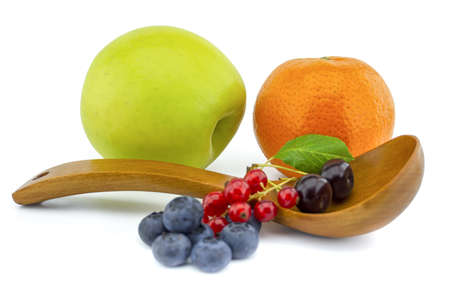 Fresh seasonal fruit still life with assorted berries including blueberries, cherries and red currants on wooden spoons with apple and orange on a white background with copyspaceの写真素材