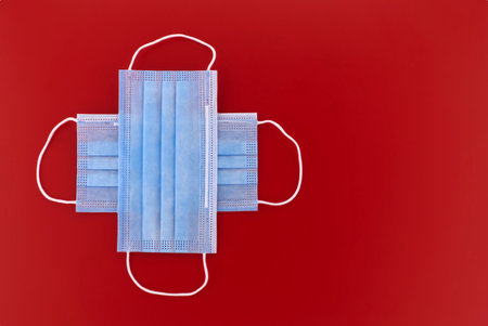 Crossed protective surgical face masks over a red background with copyspaceの写真素材