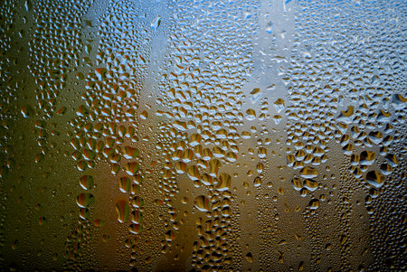 Condensation with beaded moisture droplets on the outside of a cold glass or bottle in a close up full frame background textureの写真素材