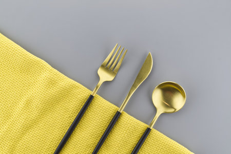 Set of stylish black and gold cutlery on a two tone grey and yellow background with copy space viewed as a flat lay. Main color trend of the yearの写真素材