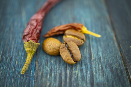 Dried red chili pepper and roasted coffee beans on wooden background. Macro photoの写真素材