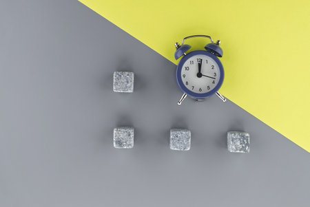 Alarm clock on a two tone grey and yellow background with copy space viewed as a flat lay....