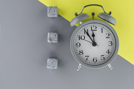 Alarm clock on a two tone grey and yellow background with copy space viewed as a flat lay. Renovation and color trends conceptの写真素材