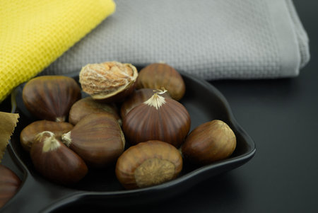Fresh chestnuts also called sweet chestnut, Castanea sativa, Spanish chestnut in a black pan, low angle view and shallow focusの写真素材