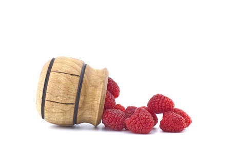 Heap of red ripe raspberry berries fall out of a wooden container isolated on white backgroundの写真素材