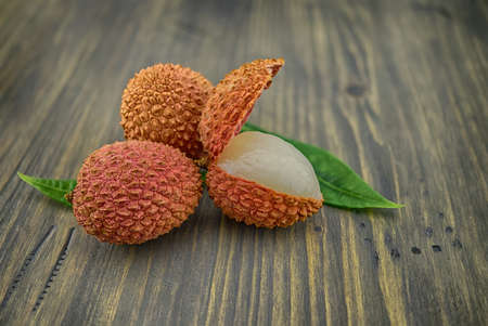 Lychee fruit whole and opened with green leaves decoration on rustic wood backgroundの写真素材