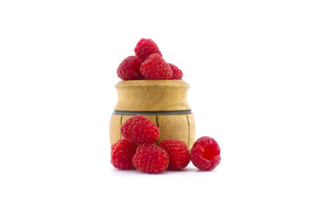 Ripe raspberry fruits and a small wooden pot isolated on white backgroundの写真素材