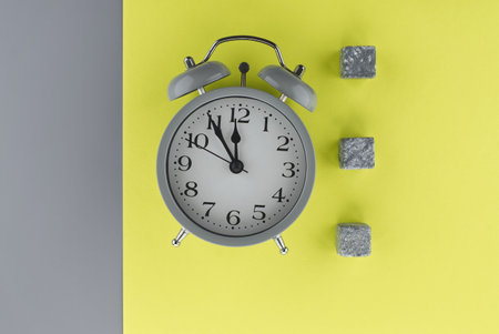 Alarm clock on a two tone grey and yellow background with copy space viewed as a flat lay. Renovation and color trends conceptの写真素材