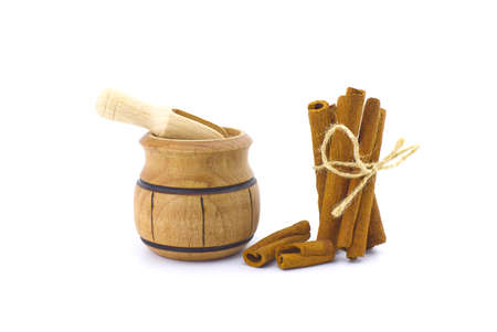 Cinnamon sticks bundle tied with jute string and a small wooden pot isolated on white backgroundの写真素材