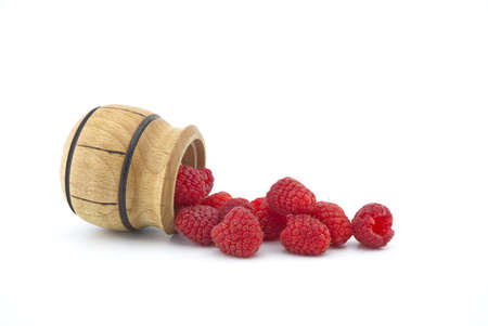 Heap of red ripe raspberry berries fall out of a wooden container isolated on white backgroundの写真素材