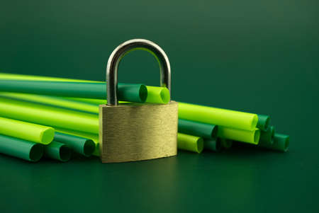 Padlock and plastic drink straws on a green background. Ban on plastic drinking straws conceptの写真素材