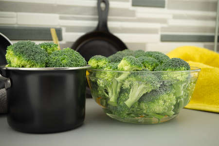 Prepare broccoli for eating on the kitchen table, broccoli florets soaked in a clear bowの写真素材