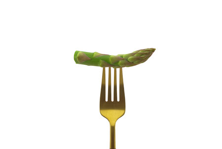Asparagus pinned on a golden fork isolated on a white backgroundの写真素材