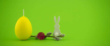 Minimalistic style Easter banner with yellow egg shaped candle, pussy willow branch and Easter Bunny figure over a green background with free copy space for your textの写真素材