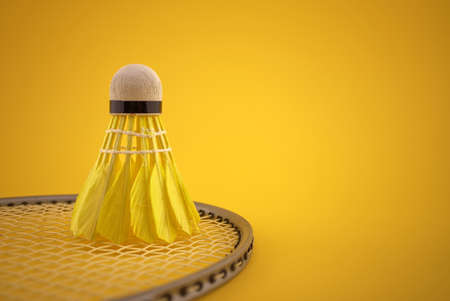 Badminton feather shuttlecock on badminton racket over a yellow background with copy spaceの写真素材