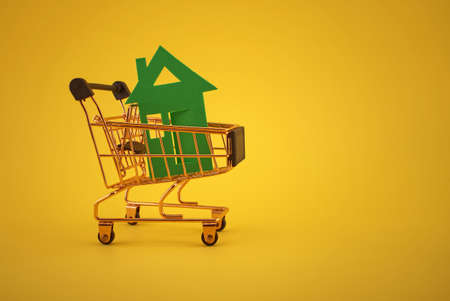 Buy real estate concept with house and shopping cart in the yellow backgroundの写真素材