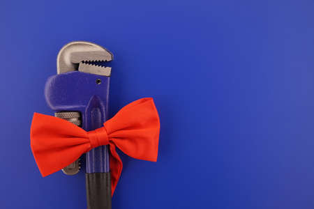 Pipe wrench tied with a red bow over a blue background with copy space. Labor Day or fathers day conceptの写真素材