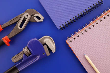 Plumbing equipment and wire bound open notebooks on blue background, plumbing estimating concept with free copy space for textの写真素材