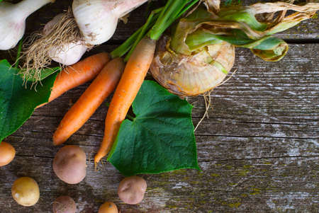 Assortment of freshly harvested healthy farm vegetables in a flat lay still life on a rustic table...
