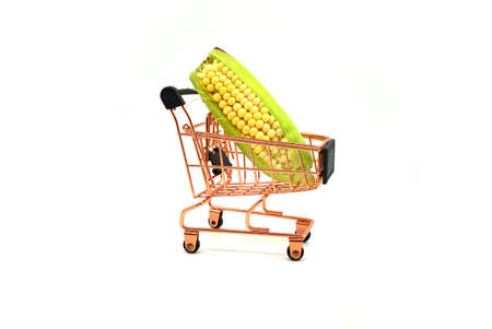 Fresh corn on the cob in a small shopping cart over a white background in a diet and nutrition...