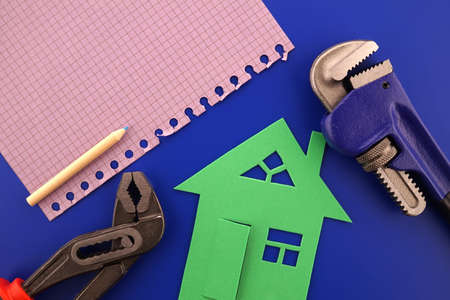 House ownership, building or construction still life concept with a flat lay of notebooks, wrench, purse, pencil and colorful cutout paper homesの写真素材