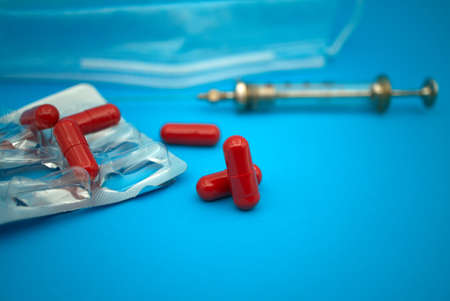 Medical, Covid-19 and healthcare background with red capsules scattered on blue alongside an empty...