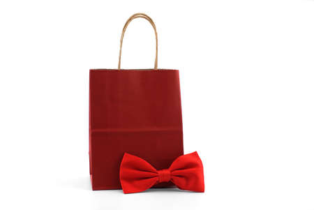 Red paper shopping bag with red bow tie over a white background. Gifts for gentleman and shopping conceptの写真素材