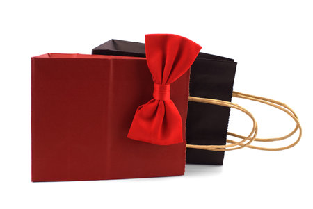 Black and red paper shopping bags with red bow tie over a white background. Gifts for gentleman and shopping conceptの写真素材