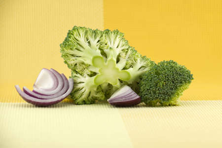 Fresh raw green broccoli near slices red onions on the kitchen table