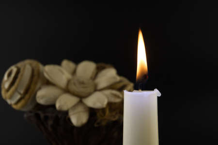 Close-up of a burning candle and flowers illuminated by the candlelight in the darkness with free copy spaceの写真素材